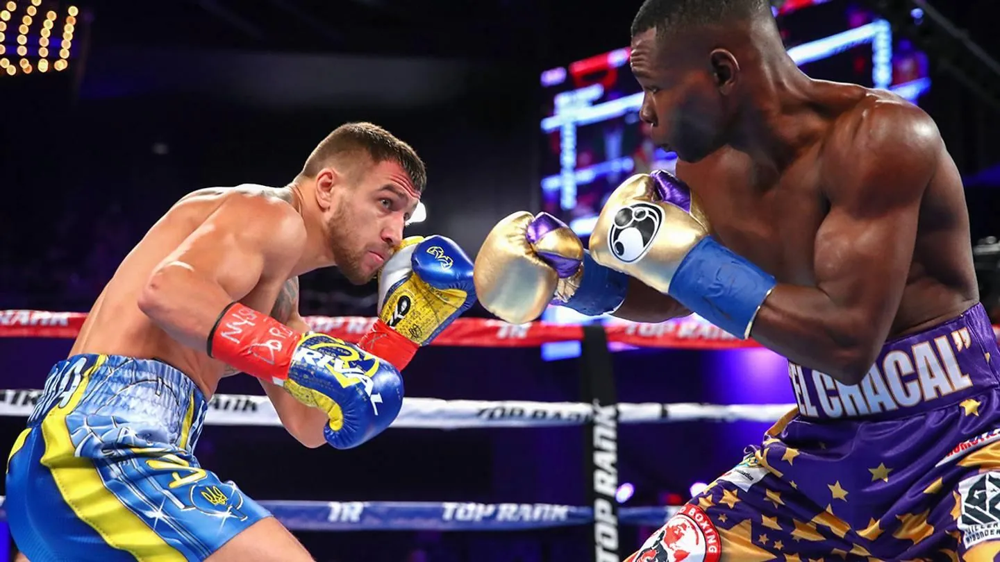 Two gloved boxers facing each other during a bout in a brightly lit ring